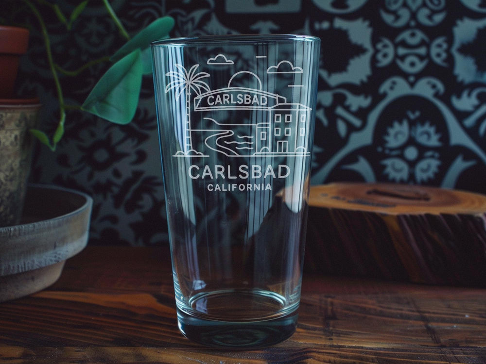 Carlsbad California Pint Glass with Ocean View, Beach Scene, Palm Trees, and Coastal Landmarks Design